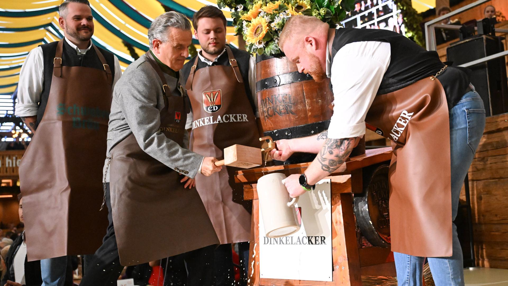 Frank Nopper (2.v.l, CDU), Oberbürgermeister von Stuttgart, sticht beim Stuttgarter Volksfest Canstatter Wasen bei der Eröffnung das erste Fass Bier mit zwei Schlägen an.