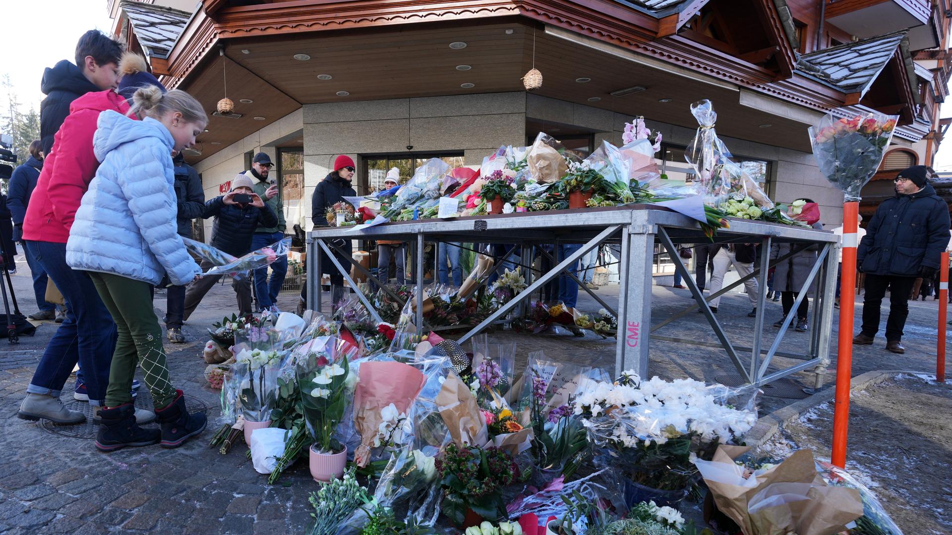 Menschen bringen Blumen und Briefe in die Nähe der abgeriegelten Bar, in der das Feuer ausgebrochen war.