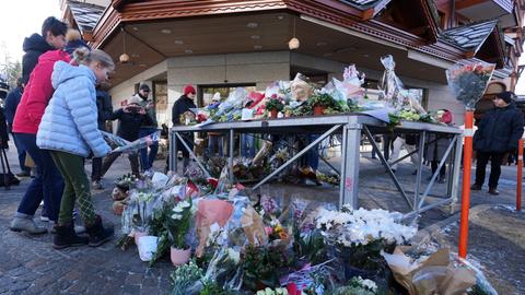 Menschen bringen Blumen und Briefe in die Nähe der abgeriegelten Bar, in der das Feuer ausgebrochen war.