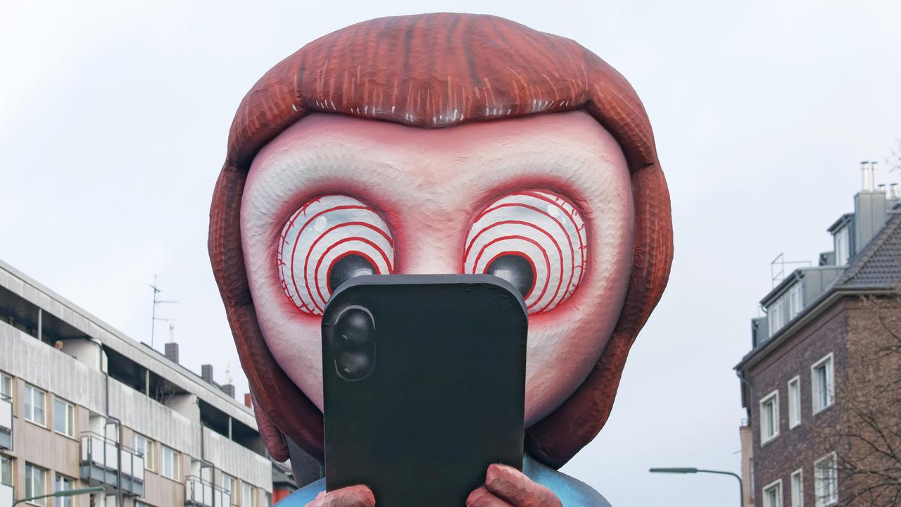 Mottowagen beim Düsseldorfer Rosenmontagszug: Ein aus Pappmaché gebautes Kind schaut gebannt auf ein Smartphone. In den Augen des Kindes sind Hypnose-Ringe zu sehen. 