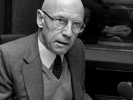 Schwarz-Weiß-Aufnahme von Michel Foucault, der in einem Radiostudio sitzt.