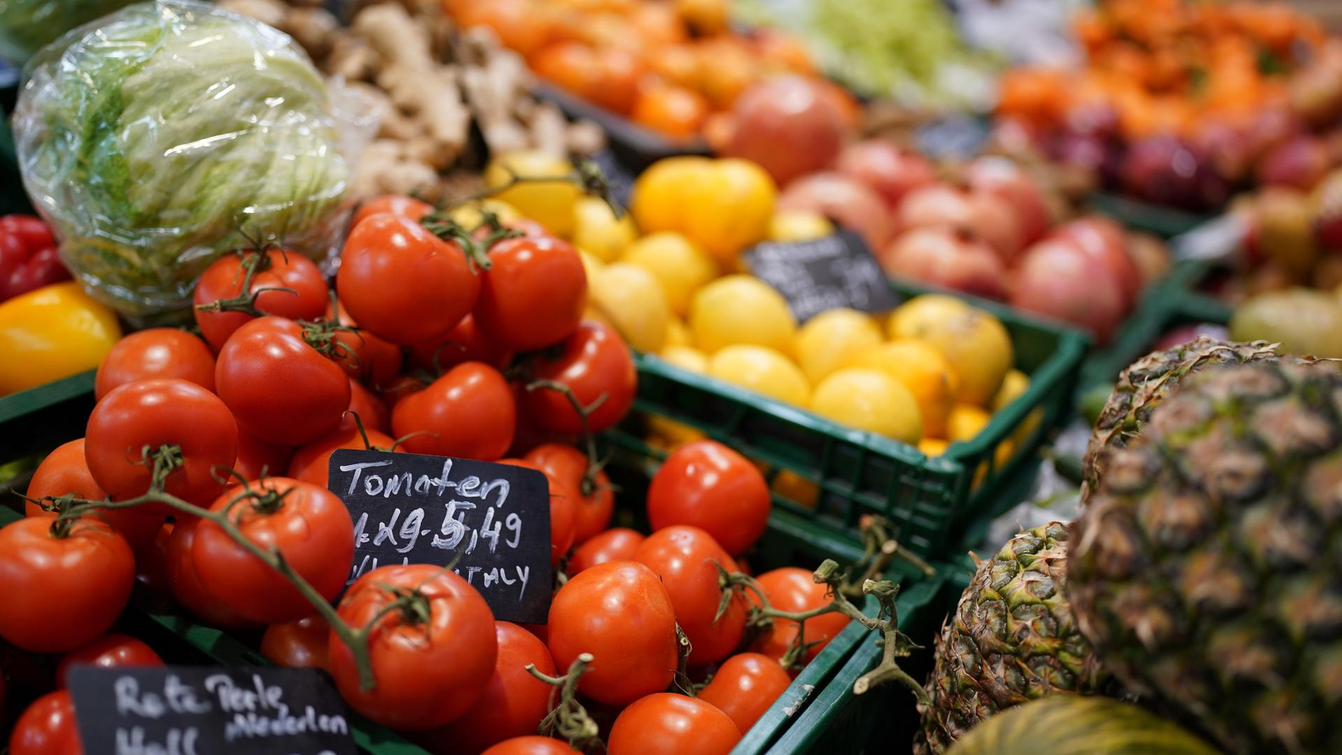 Tomaten, Ananas, Kopfsalat und verschiedene Früchte liegen in der Auslage eines kleinen Supermarktes.