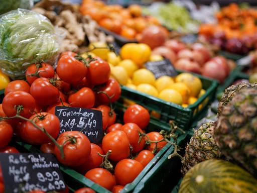 Tomaten, Ananas, Kopfsalat und verschiedene Früchte liegen in der Auslage eines kleinen Supermarktes.