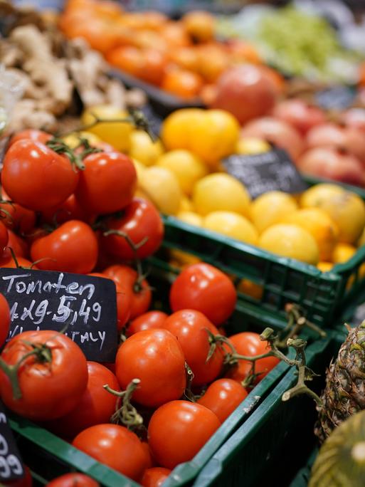 Tomaten, Ananas, Kopfsalat und verschiedene Früchte liegen in der Auslage eines kleinen Supermarktes.