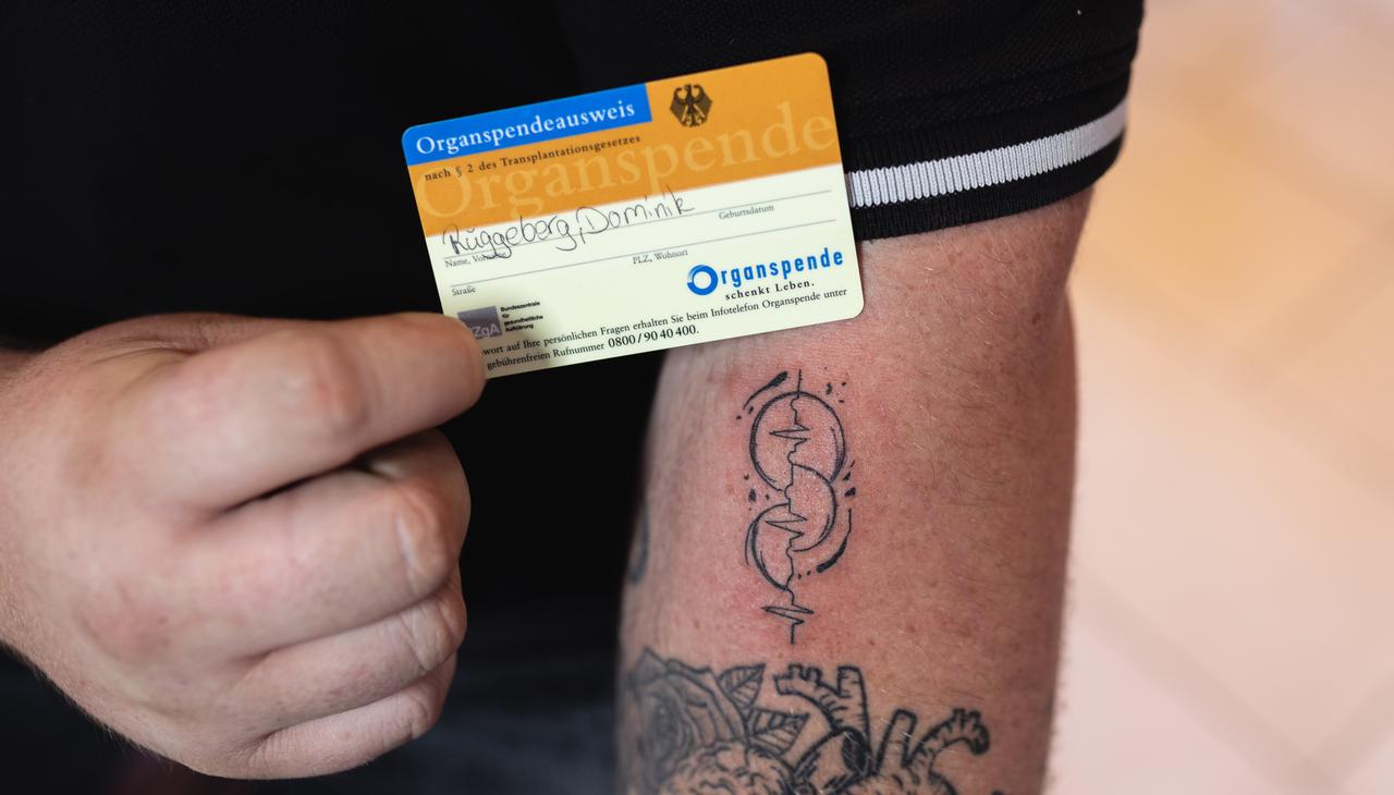 Ein Mann mit einem Opt-Ink-Tattoo für Organspender und einem Organspendeausweis.