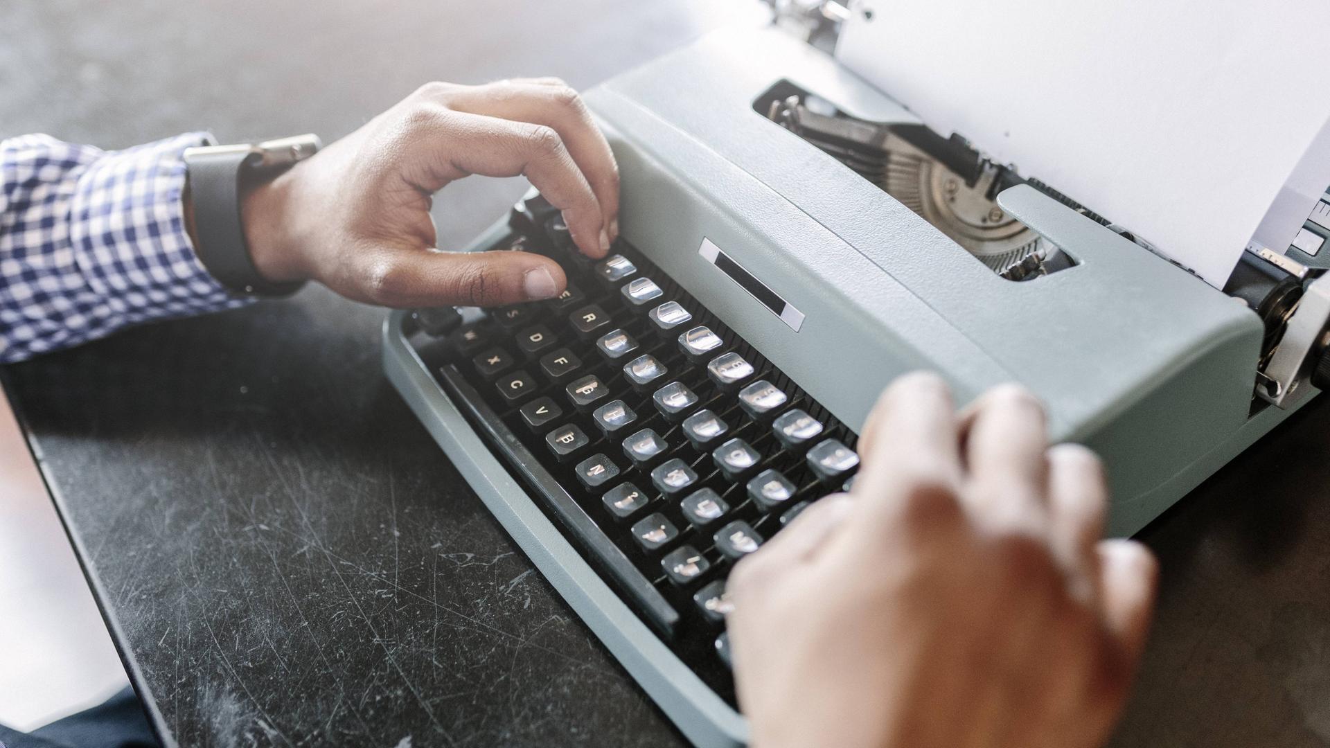 Hände tippen auf einer Schreibmaschine. 