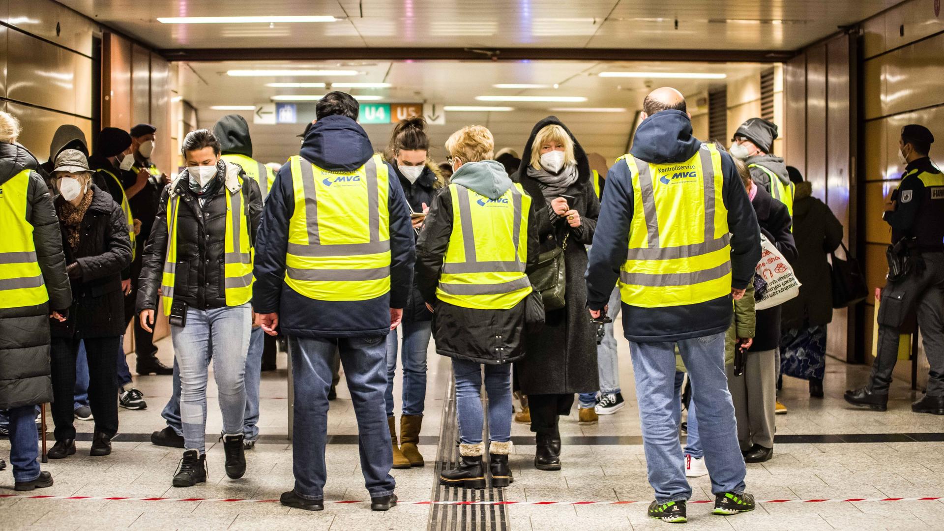 Menschen in gelben Westen blockieren den Ausgang einer U-Bahnstation und kontrollieren die Impfnachweise der Passanten.