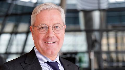Norbert Röttgen steht im Reichstagsgebäude und lächelt in die Kamera