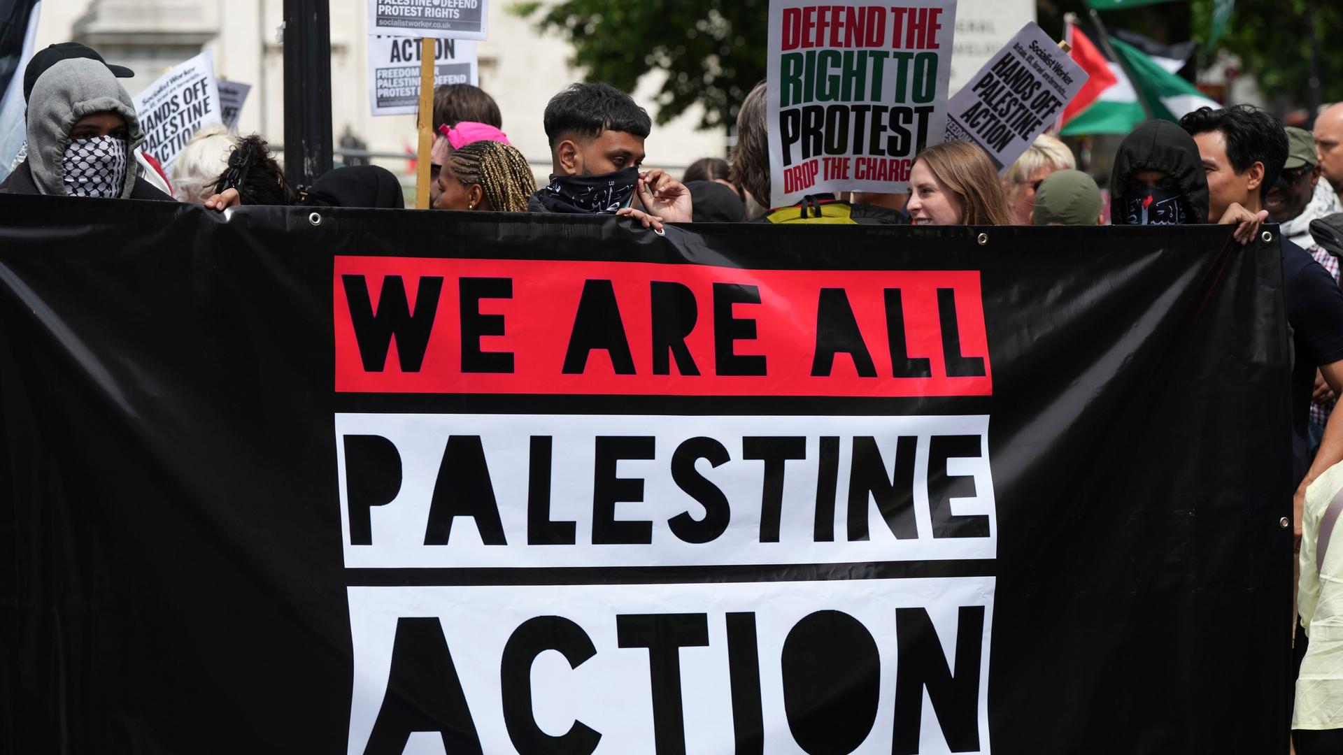 Teils vermummte Demonstranten in London halten ein Banner der Gruppierung "Palestine Action".