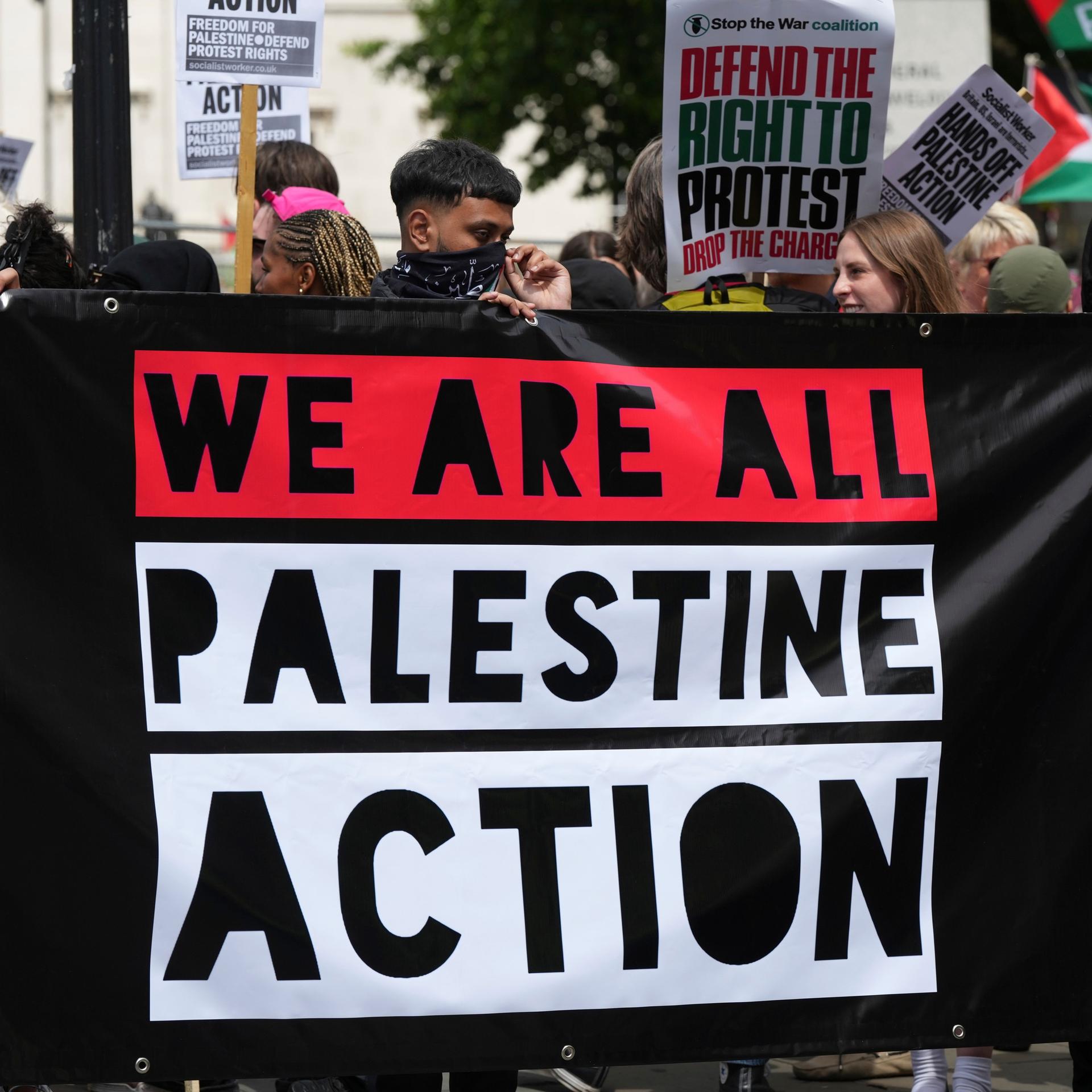 Teils vermummte Demonstranten in London halten ein Banner der Gruppierung "Palestine Action".