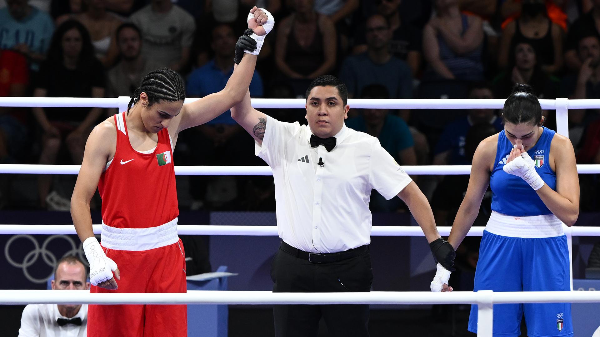 Zwei Frauen mit einem Ringrichter nach einem Boxkampf.