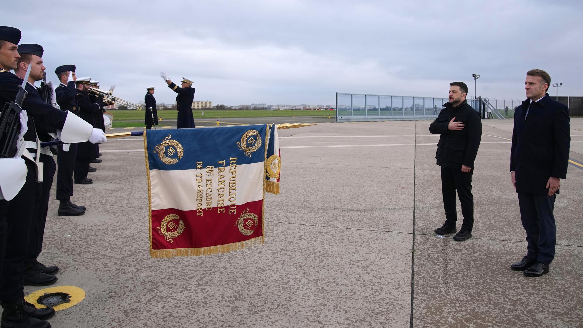 Der französische Präsident Emmanuel Macron (r) und der ukrainische Präsident Wolodymyr Selenskyj (2.v.r) hören auf dem Luftwaffenstützpunkt Villacoublay bei Paris die Nationalhymnen. Der französische Präsident Emmanuel Macron (r) und der ukrainische Präsident Wolodymyr Selenskyj (2.v.r) hören auf dem Luftwaffenstützpunkt Villacoublay bei Paris die Nationalhymnen.