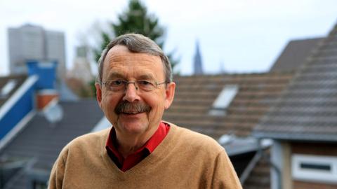 Portrait des Soziologen Wolfgang Streeck vor dem Kölner Stadtpanorama