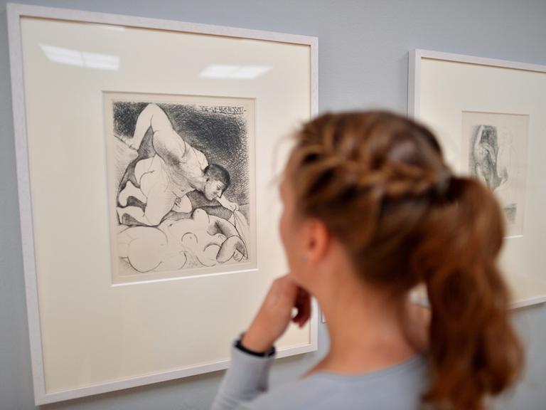 Eine Frau betrachtet die Picasso-Radierung "Mann, eine Frau entschleiernd". Sie gehört zu der nach einem Kunsthändler benannten Suite Vollard.