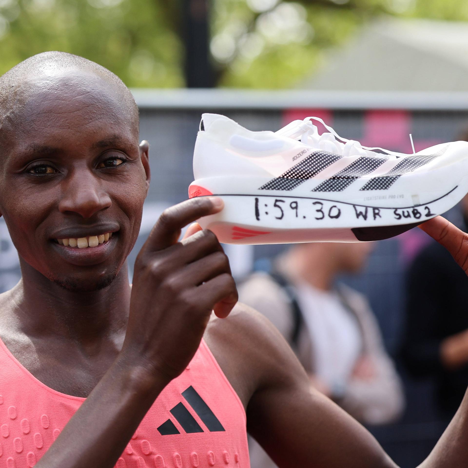 Sabastian Sawe hält seinen Sportschuh mit dem Marathon-Rekordwert in der Hand.