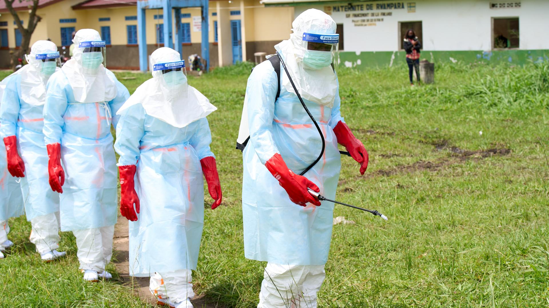 Mitarbeitende im Bezirk Rwampara im Kongo mit Desinfektionsmitteln. Sie sind komplett in weiße Overalls gehüllt, die sie vor dem Virus schützen sollen. In der Hand hält einer eine Spritze, wie man sie von Pflanzenschutzmitteln kennt. Mitarbeitende im Bezirk Rwampara im Kongo mit Desinfektionsmitteln. Sie sind komplett in weiße Overalls gehüllt, die sie vor dem Virus schützen sollen. In der Hand hält einer eine Spritze, wie man sie von Pflanzenschutzmitteln kennt.