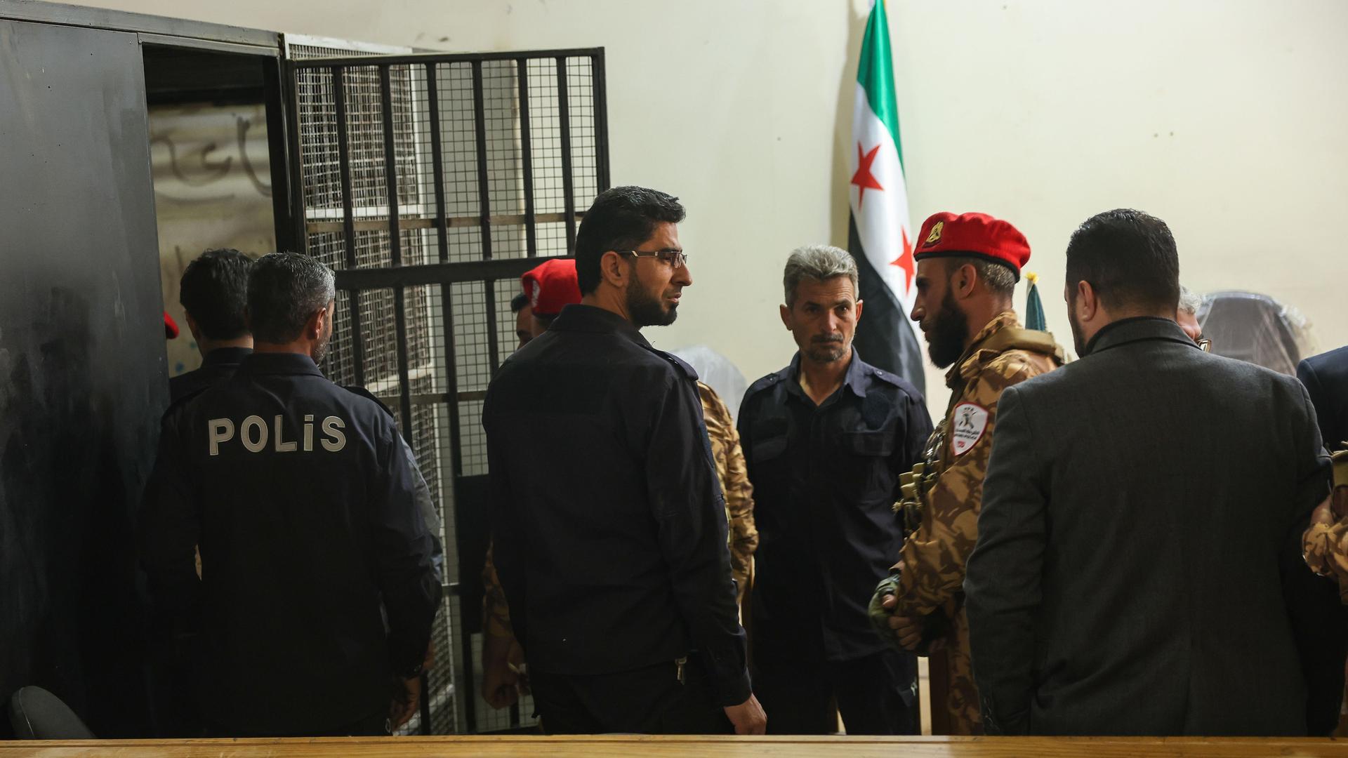 Sicherheitskräfte stehen vor einer Arrestzelle während des ersten öffentlichen Prozesses in Syrien im Zusammenhang mit den tödlichen Zusammenstößen im März in den Küstenprovinzen des Landes im Justizpalast. 