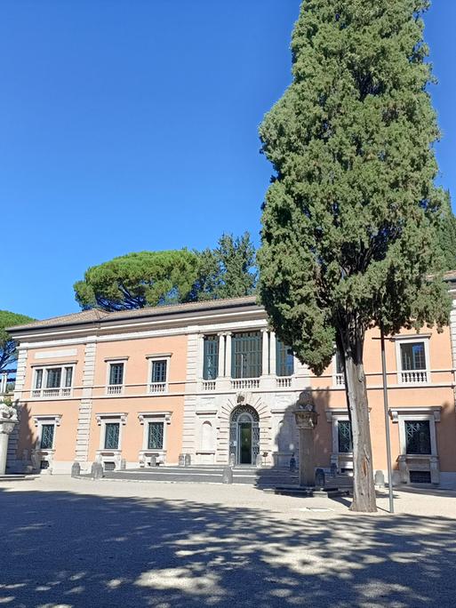 Zu sehen ist die Villa Massimo, ein in orangetönen gehaltenes Gebäude