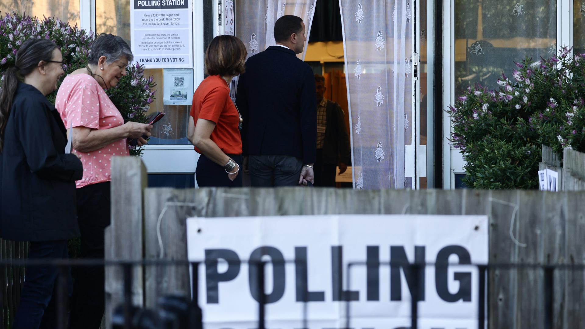 Das Foto zeigt Menschen, die bei der Parlamentswahl in Großbritannien darauf warten, ihre Stimme abzugeben.