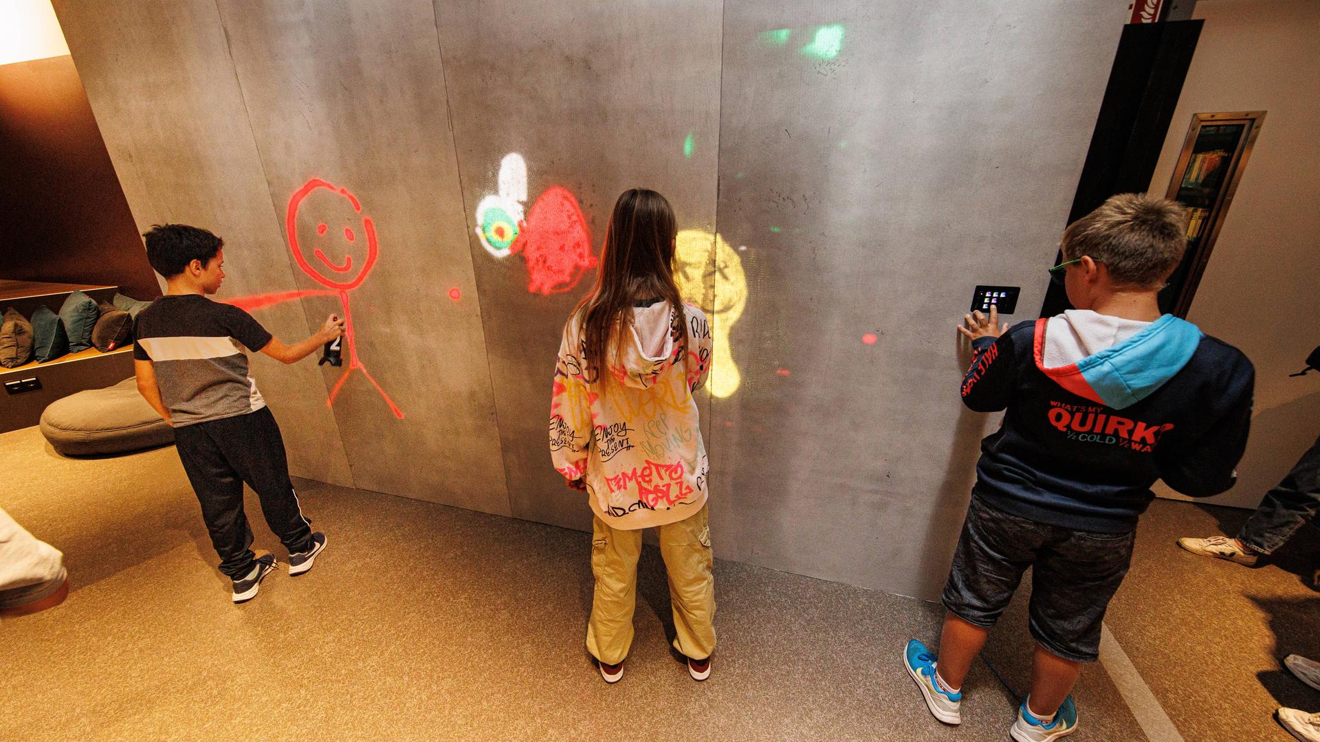 Kinder besprühen eine digitale Graffiti-Wand in der Düsseldorfer Zentral-Bibliothek.