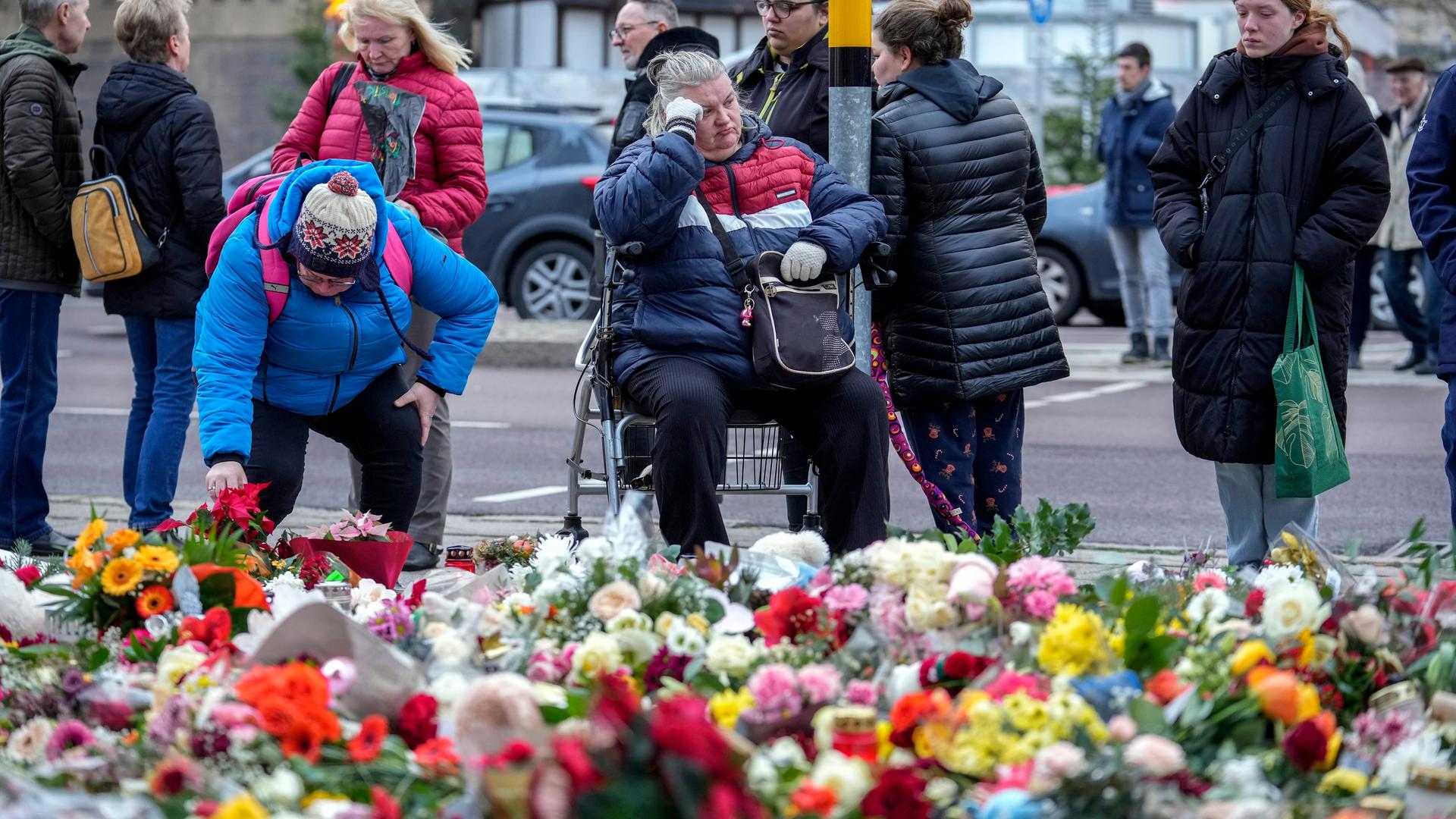 Menschen legen am 23.12.2024 Blumen in der Nähe des Weihnachtsmarktes in Magdeburg ab und gedenken der Opfer des Anschlags. 