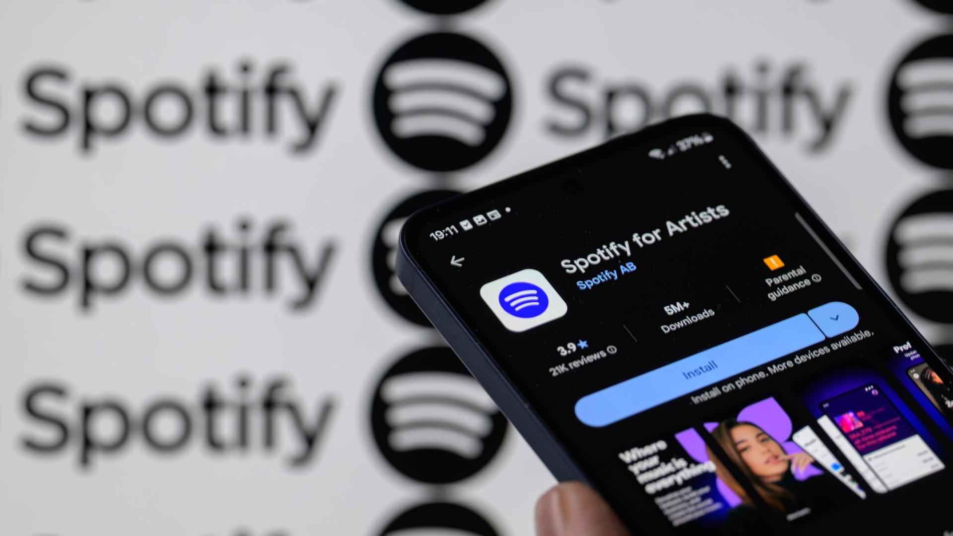 Die Spotify for Artists-App wird auf einem Mobiltelefon angezeigt, im Hintergrund ist das Spotify-Logo zu sehen.