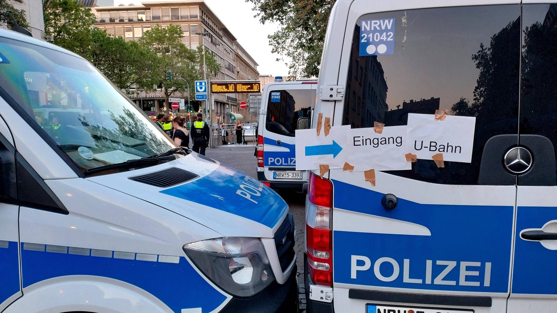 Zu sehen sind mehrere Polizeifahrzeuge an einer Düsseldorfer U-Bahn-Haltestelle. Auf Zetteln steht "Eingang U-Bahn".