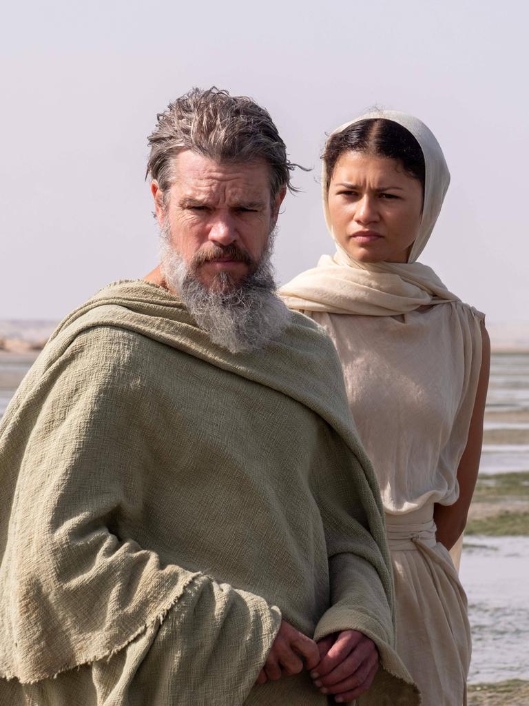 Matt Damon als Odysseus und Zendaya als Athena stehen vor einer Wüsten-ähnlichen Landschaft. Matt Damon als Odysseus und Zendaya als Athena stehen vor einer Wüsten-ähnlichen Landschaft.