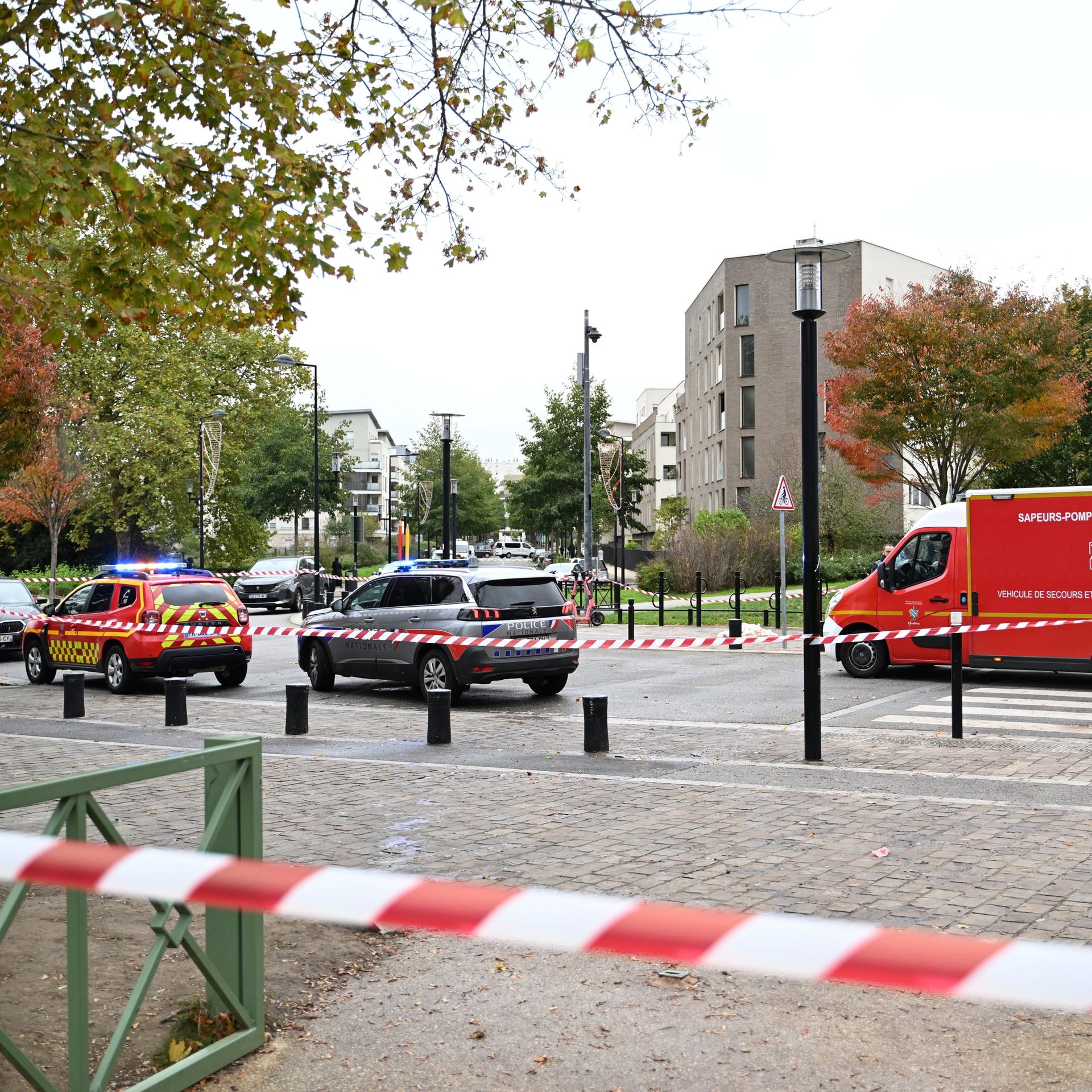 Zu sehen sind rot-weißes Absperrband und Einsatzfahrzeuge von Polizei und Sanitätern.