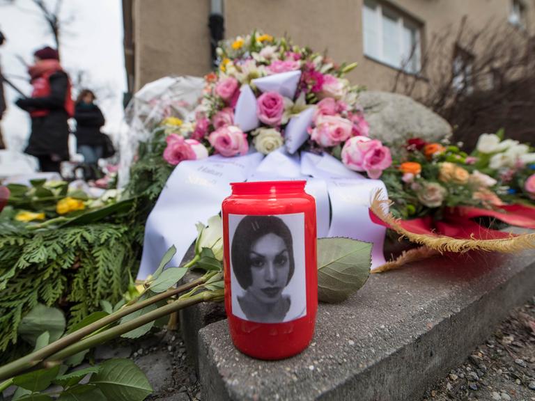 Ein Grablicht auf einem mit Blumen geschmückten Grab trägt das Foto der 2005 in Berlin ermordeten Hatun Sürücü.