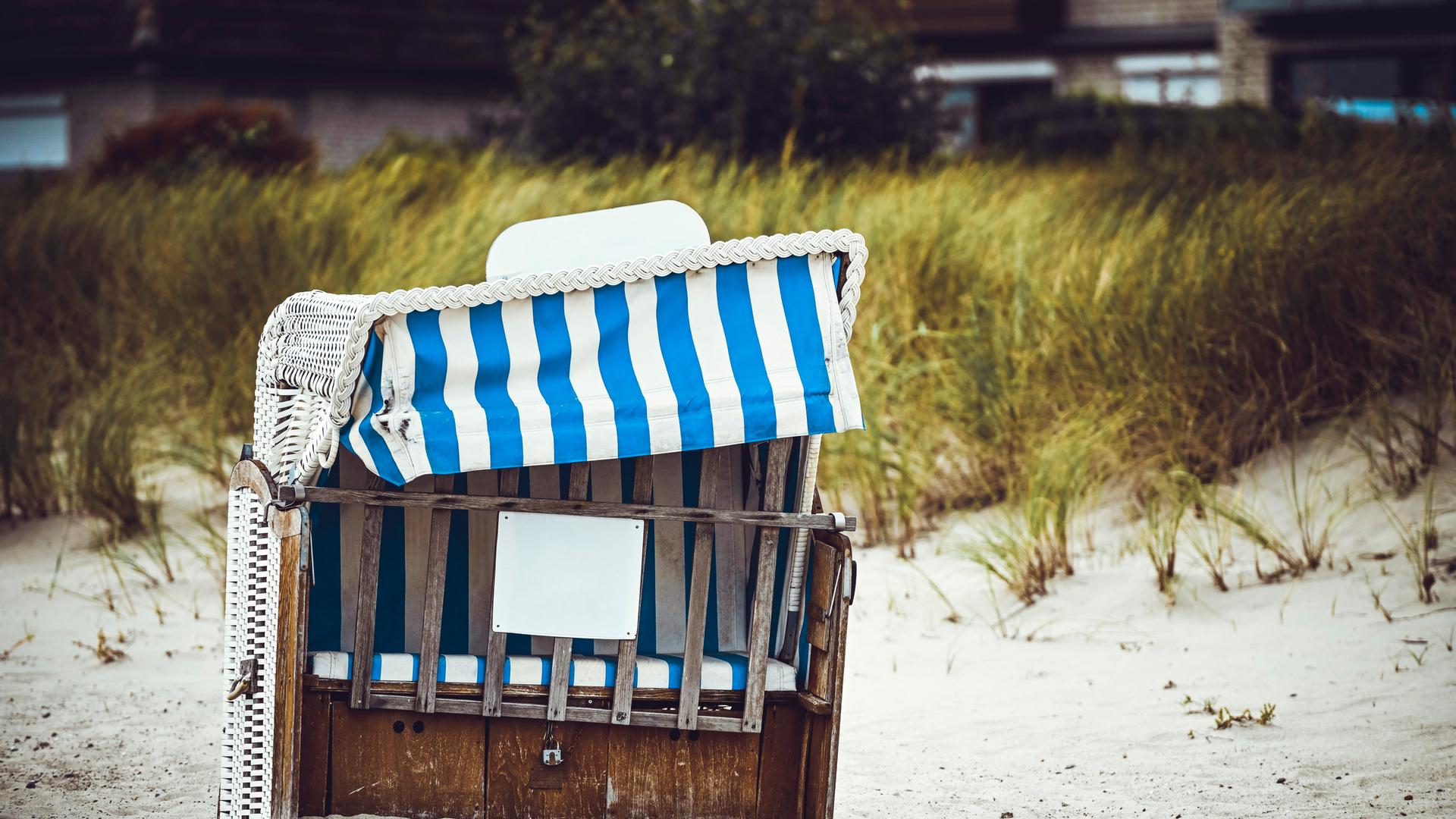 Ein kaputter blau-weißer Strandkorb steht am Ostseestrand. Ein kaputter blau-weißer Strandkorb steht am Ostseestrand.