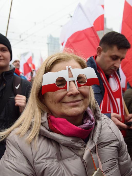 Eine Frau trägt eine Brille, die an polnische Flaggen erinnert, während sie am 11. November 2023 in Warschau, Polen, am 105. Jahrestag der Wiedererlangung der Unabhängigkeit Polens teilnimmt. 