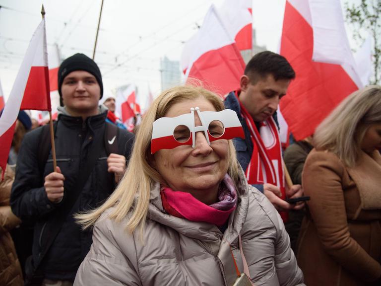 Eine Frau trägt eine Brille, die an polnische Flaggen erinnert, während sie am 11. November 2023 in Warschau, Polen, am 105. Jahrestag der Wiedererlangung der Unabhängigkeit Polens teilnimmt. 