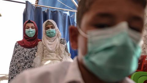 Das Foto zeigt drei syrische Kinder und Jugendliche in einem Waisenhaus in Idlib mit Gesichtsmasken. 