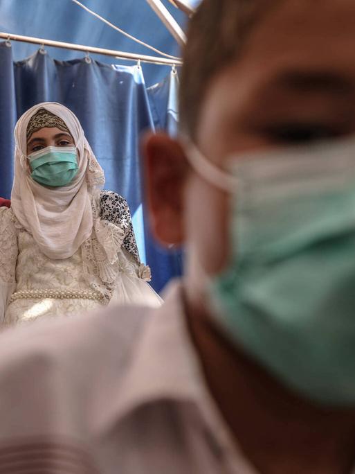 Das Foto zeigt drei syrische Kinder und Jugendliche in einem Waisenhaus in Idlib mit Gesichtsmasken. 