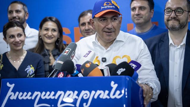 Der armenische Ministerpräsident Paschinjan steht lächelnd an einem Rednerpult.