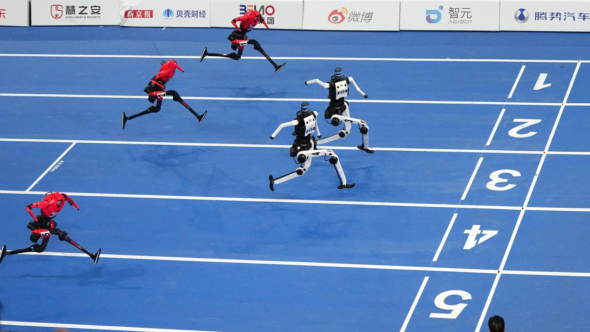 Humanoide Roboter laufen auf einer Leichtathletikbahn ins Ziel.