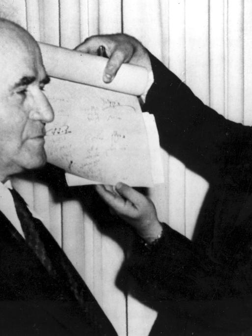 Ein Mann hält das Dokument hoch, mit dem die Gründung des Staates Israel proklamiert wird. Premierminister David Ben-Gurion steht am 14. Mai 1948 links neben dem Mann