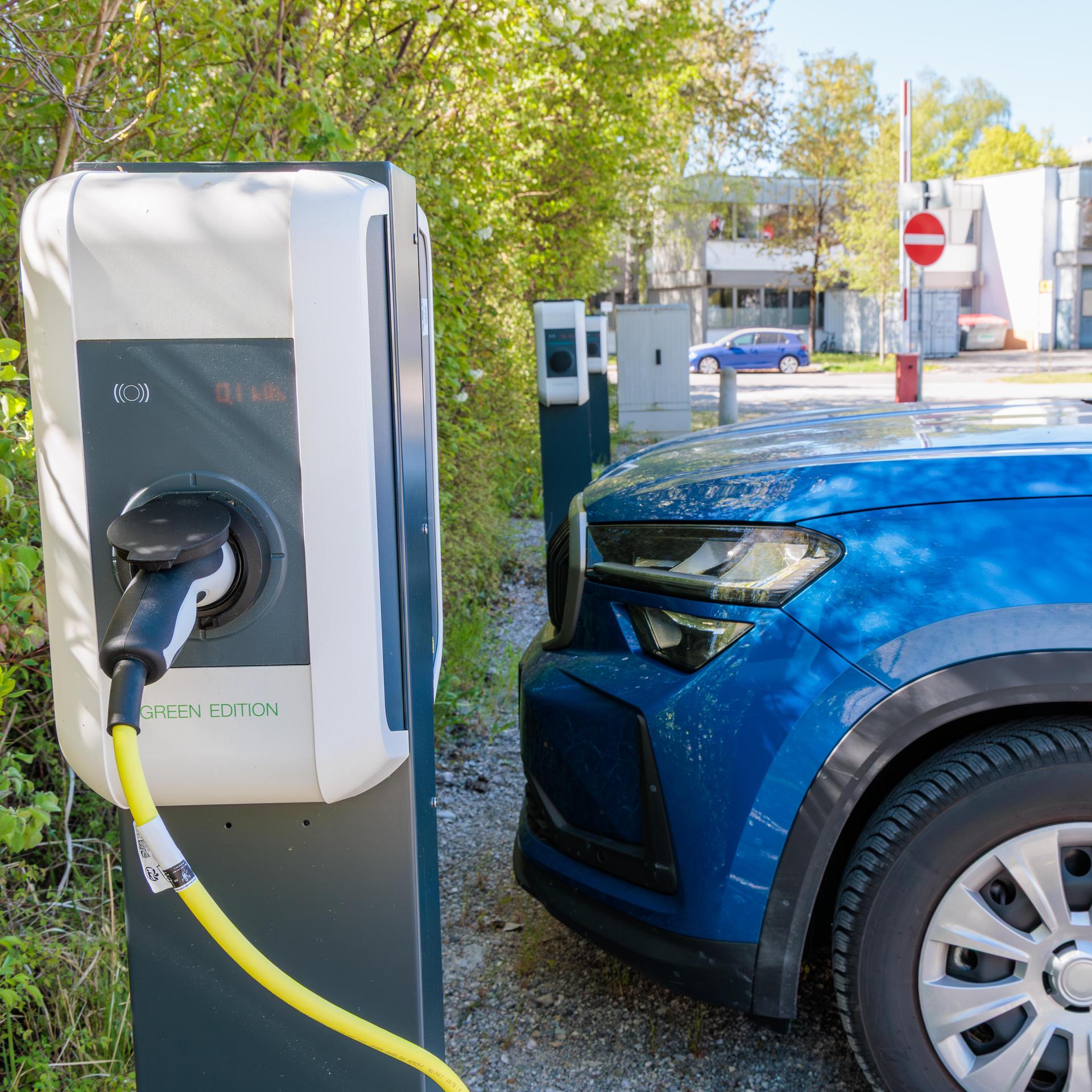 Aufladen eines Elektroautos an einer öffentlichen Station, angeschlossen an ein Wandladegerät in einem städtischen Gebiet, nachhaltige Mobilität, Verkehr mit sauberer Energie, umweltfreundliche Technologie