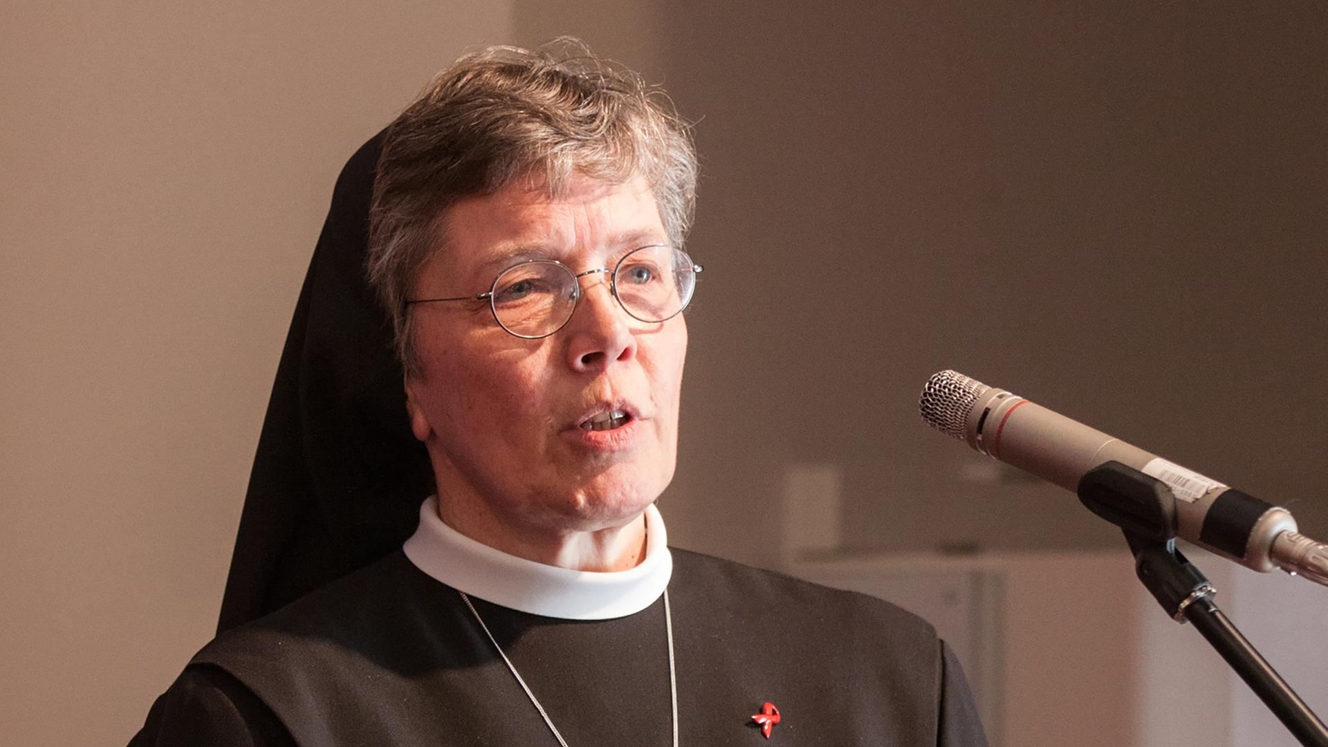 Hannelore Huesmann steht in Ordenskleidung am Mikrofon und spricht Hannelore Huesmann steht in Ordenskleidung am Mikrofon und spricht