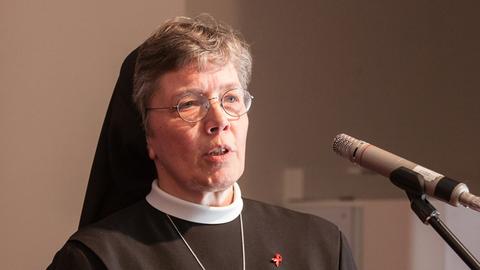 Hannelore Huesmann steht in Ordenskleidung am Mikrofon und spricht Hannelore Huesmann steht in Ordenskleidung am Mikrofon und spricht
