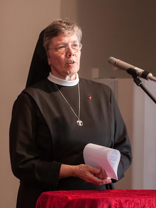 Hannelore Huesmann steht in Ordenskleidung am Mikrofon und spricht