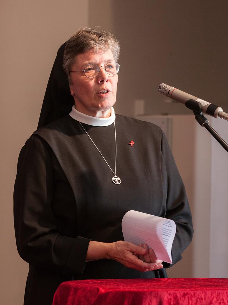 Hannelore Huesmann steht in Ordenskleidung am Mikrofon und spricht