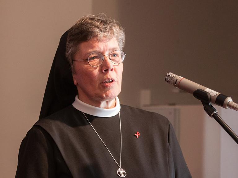 Hannelore Huesmann steht in Ordenskleidung am Mikrofon und spricht