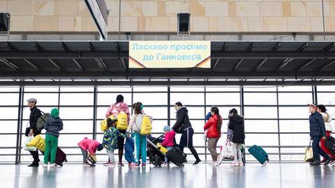 Geflüchtete aus der Ukraine laufen nach ihrer Ankunft durch die Eingangshalle vom Messebahnhof Laatzen.