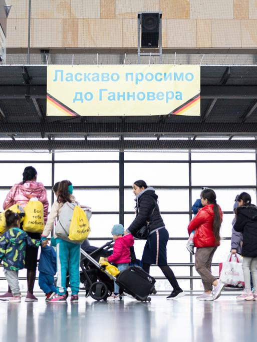 Geflüchtete aus der Ukraine laufen nach ihrer Ankunft durch die Eingangshalle vom Messebahnhof Laatzen.