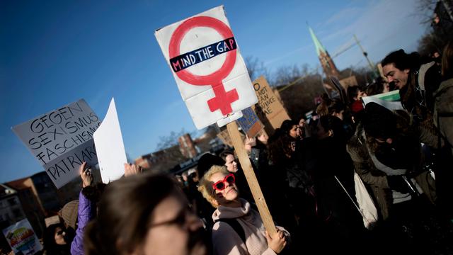 Frauen halten bei einer Demonstration Schilder hoch.