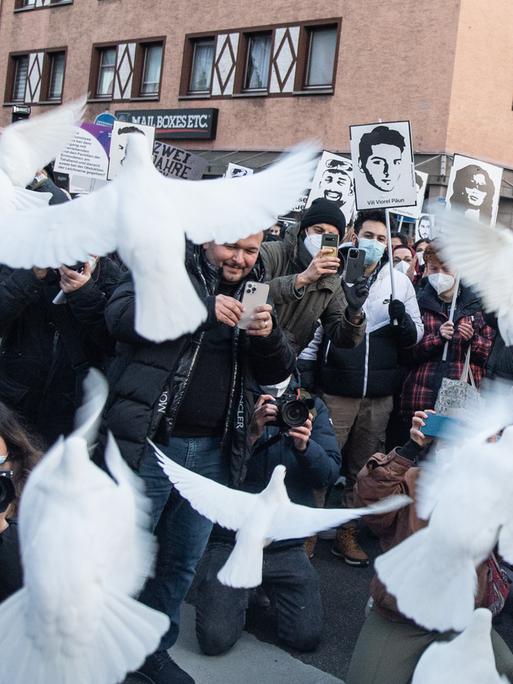 Weiße Tauben steigen in Erinnerung an die Opfer von Hanau bei einer Demonstration auf.