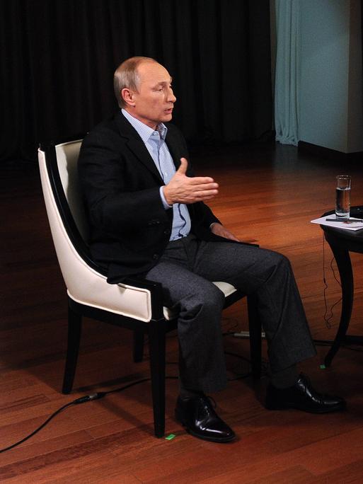 Hubert Seipel und Putin sitzen sich in auf Sesseln gegenüber und unterhalten sich.