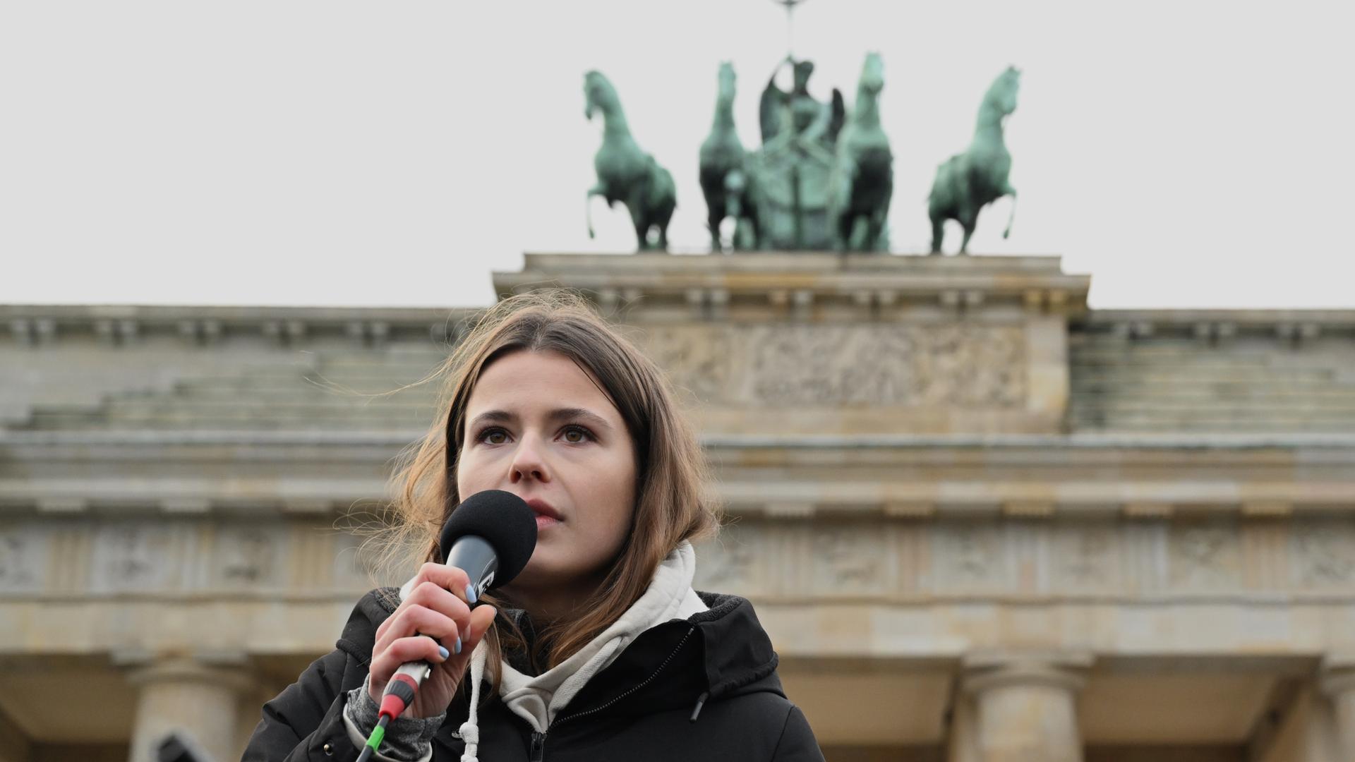 Klima-Aktivistin Luisa Neubauer spricht in ein Mikrofon. Hinter ihr das Brandenburger Tor.